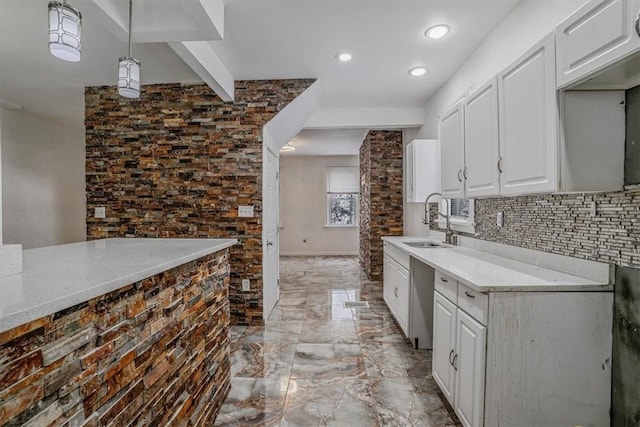 kitchen featuring white cabinetry, sink, tasteful backsplash, stainless steel dishwasher, and pendant lighting