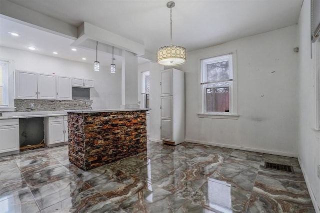 kitchen featuring white cabinetry, backsplash, and hanging light fixtures