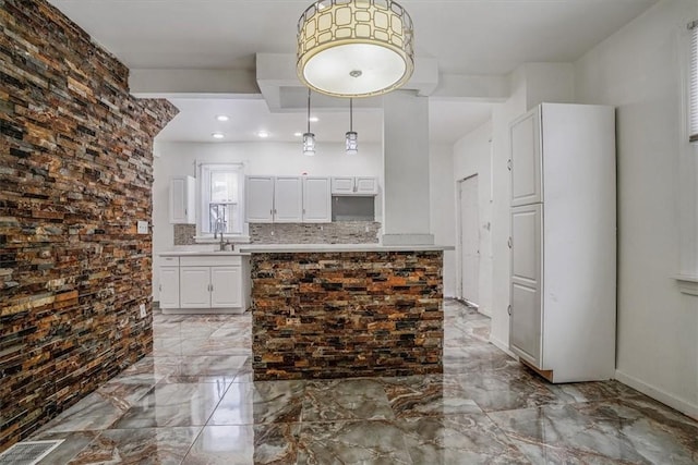 kitchen with white cabinets, backsplash, decorative light fixtures, and sink