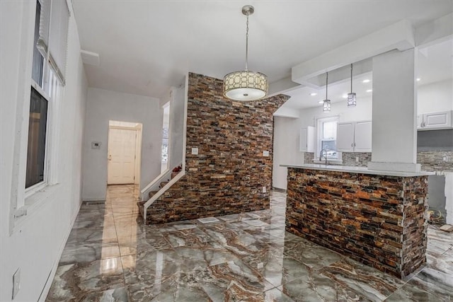 kitchen with white cabinetry, sink, kitchen peninsula, pendant lighting, and decorative backsplash