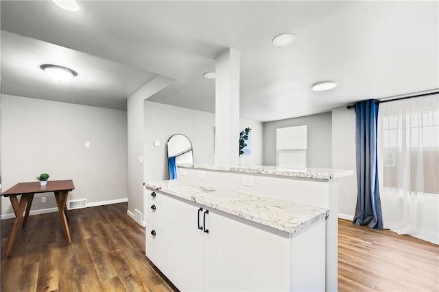 kitchen featuring light stone counters, white cabinets, dark wood-type flooring, and a kitchen island