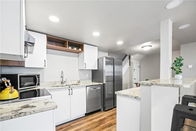 kitchen with white cabinets, a kitchen breakfast bar, stainless steel appliances, and sink