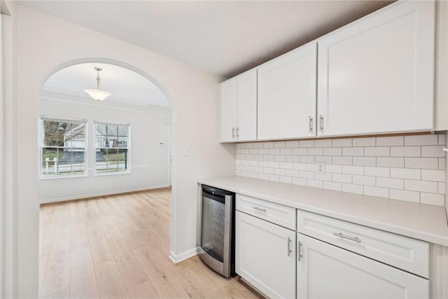 kitchen featuring white cabinets, decorative backsplash, beverage cooler, and light hardwood / wood-style flooring