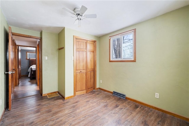 unfurnished bedroom with ceiling fan, a closet, and hardwood / wood-style flooring