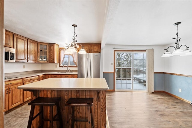 kitchen featuring a kitchen bar, stainless steel appliances, a center island, a chandelier, and sink