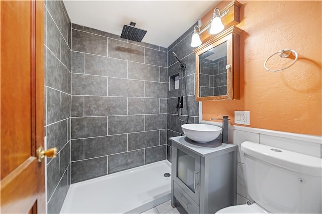 bathroom featuring toilet, vanity, and a tile shower