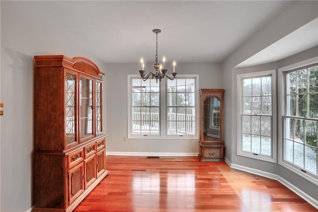 unfurnished dining area featuring light wood-type flooring and an inviting chandelier