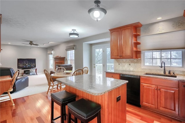 kitchen featuring sink, a center island, black dishwasher, tasteful backsplash, and a kitchen bar