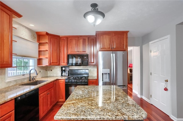 kitchen featuring black appliances, decorative backsplash, light stone countertops, and sink