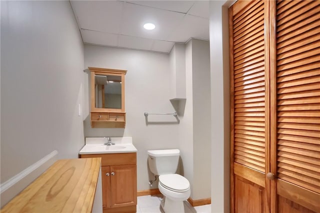 bathroom with tile patterned floors, a drop ceiling, vanity, and toilet