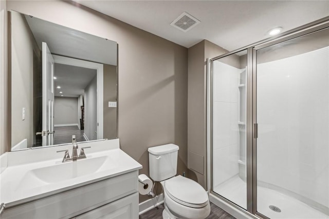 bathroom with vanity, toilet, a shower with shower door, and wood-type flooring