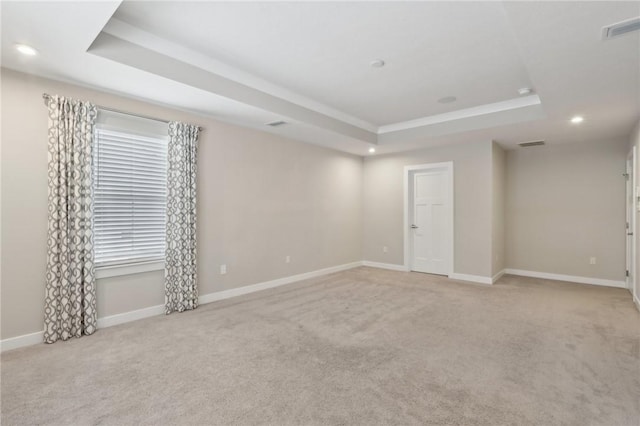 empty room with a tray ceiling and light colored carpet