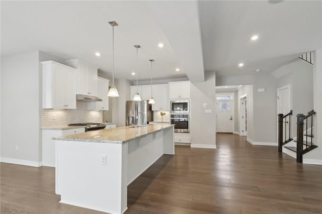 kitchen featuring backsplash, decorative light fixtures, a large island, white cabinetry, and stainless steel appliances