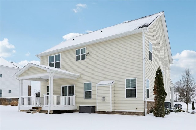 snow covered rear of property featuring a porch and central air condition unit