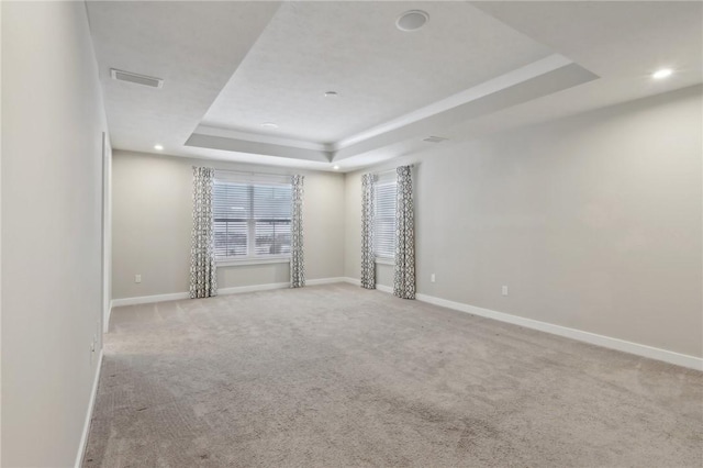 carpeted empty room featuring a tray ceiling