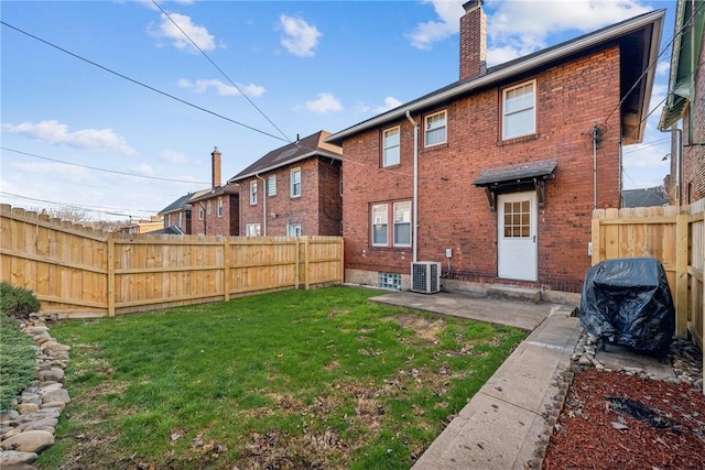 back of house featuring central AC unit, a patio area, and a lawn