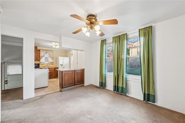 unfurnished living room featuring light carpet and ceiling fan