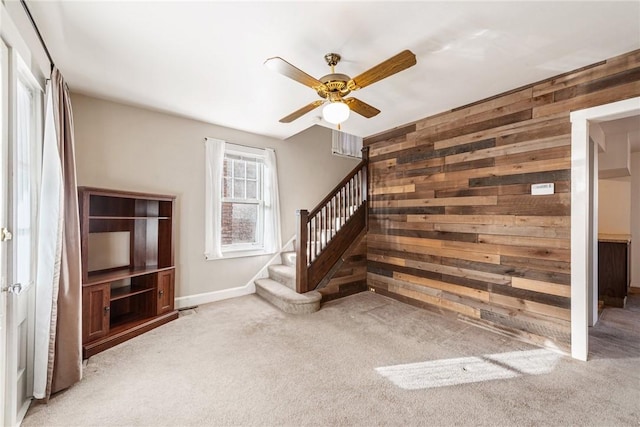 unfurnished living room featuring wood walls, carpet, and ceiling fan