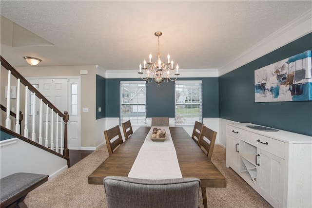 dining area with a chandelier, a textured ceiling, ornamental molding, and dark colored carpet