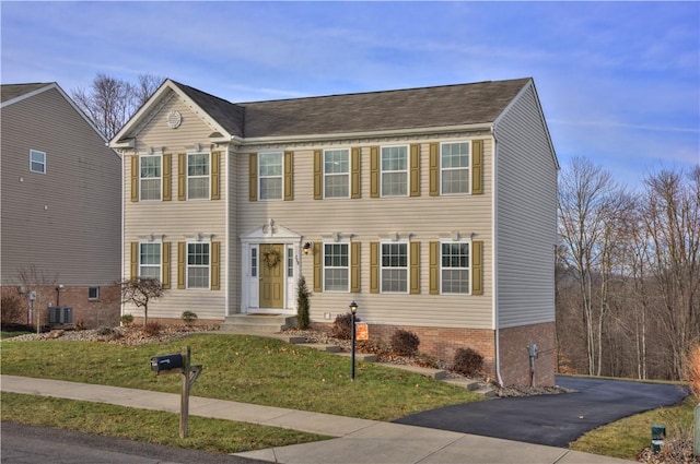 colonial house featuring central AC unit and a front yard