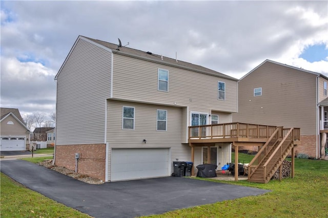 rear view of property featuring a garage, a lawn, and a wooden deck