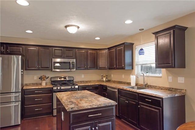 kitchen featuring appliances with stainless steel finishes, dark brown cabinetry, sink, a center island, and dark hardwood / wood-style floors