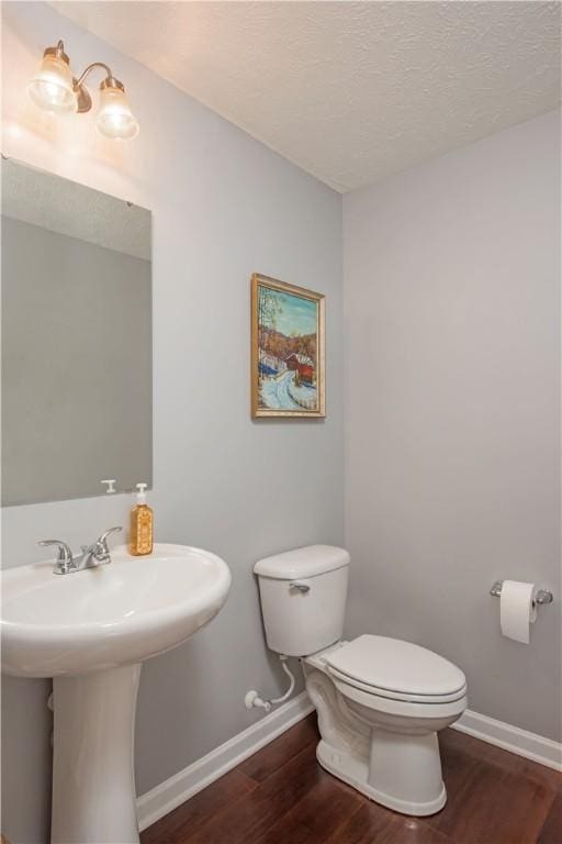 bathroom with hardwood / wood-style floors, a textured ceiling, and toilet