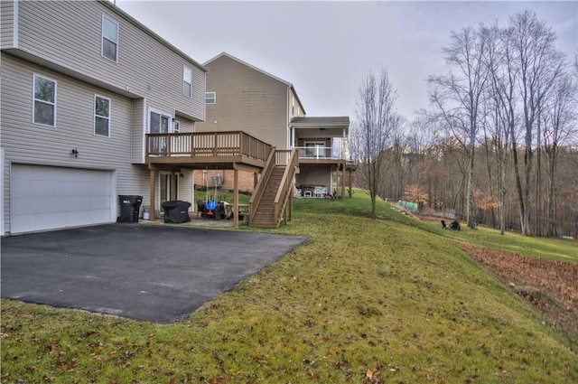 rear view of property with a lawn, a garage, and a wooden deck