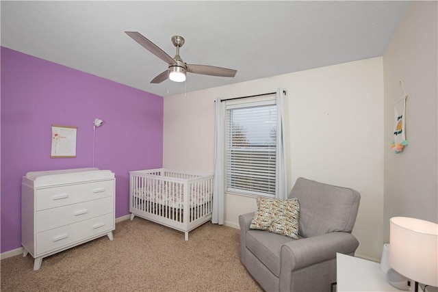 bedroom with ceiling fan, light colored carpet, and a crib