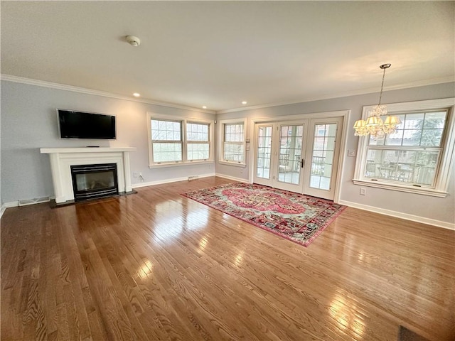 unfurnished living room with ornamental molding, a notable chandelier, and hardwood / wood-style floors