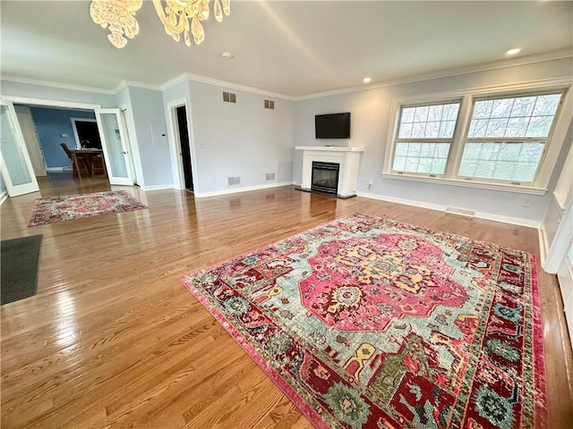 living room with crown molding, wood-type flooring, and an inviting chandelier