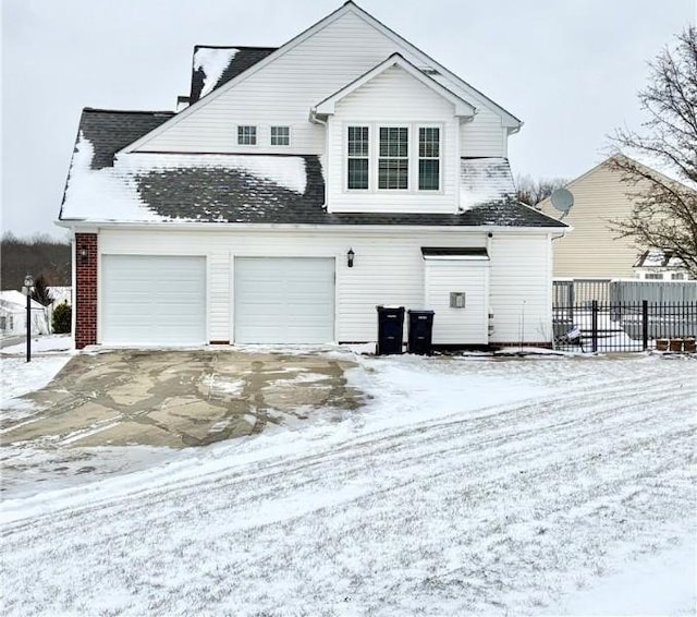 snow covered back of property with a garage