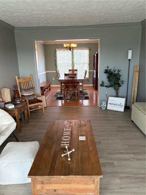 living room featuring hardwood / wood-style floors, ornamental molding, a textured ceiling, and a notable chandelier