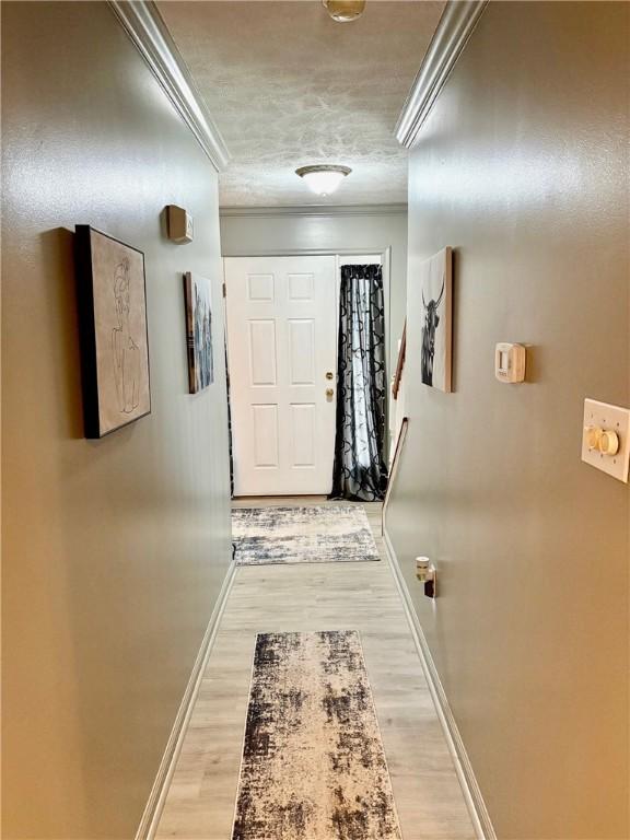 hallway featuring a textured ceiling, crown molding, and hardwood / wood-style flooring