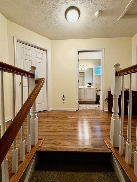 hallway featuring wood-type flooring and a textured ceiling