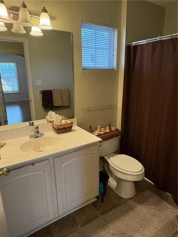 bathroom featuring a notable chandelier, toilet, and vanity