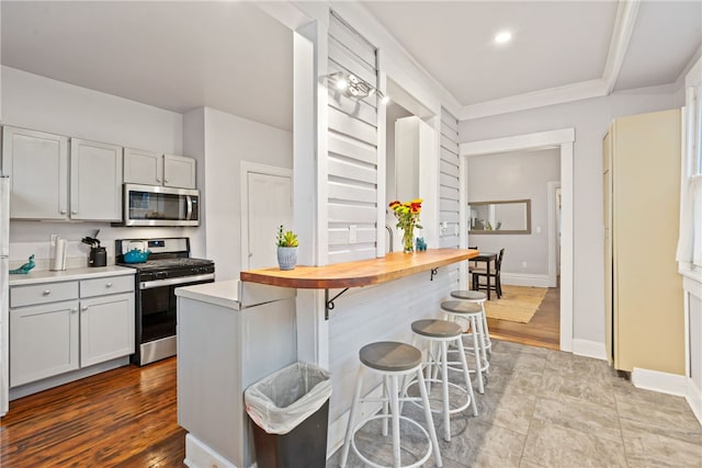 kitchen featuring a kitchen bar, butcher block counters, light hardwood / wood-style flooring, and stainless steel appliances