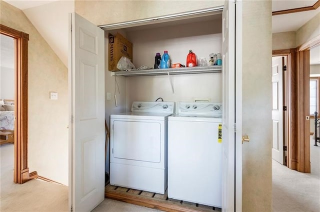 clothes washing area with washer and clothes dryer and light colored carpet