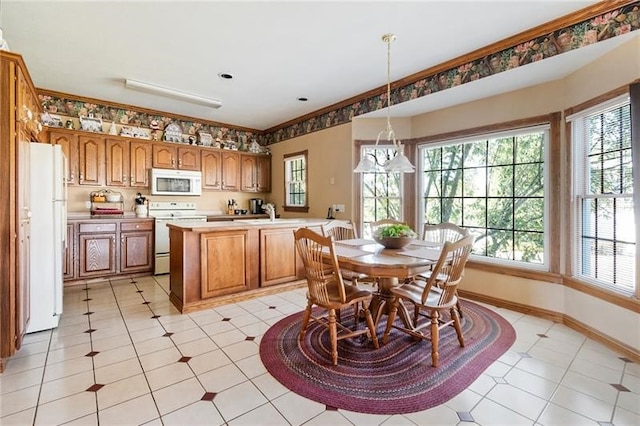 kitchen with light tile patterned flooring, white appliances, hanging light fixtures, and an island with sink