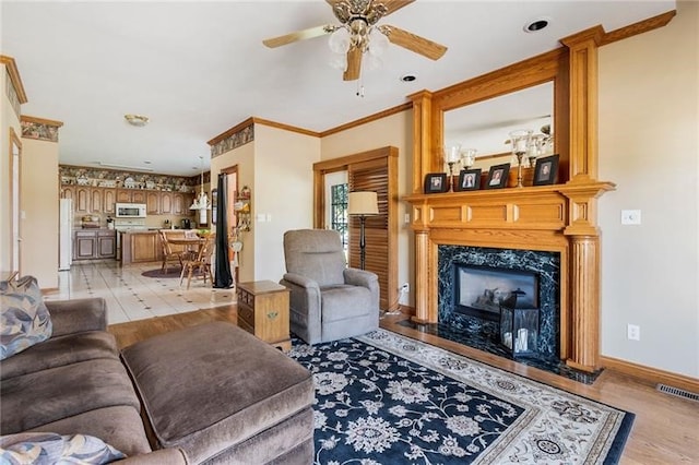 living room with ceiling fan, crown molding, and a fireplace