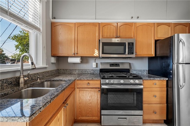 kitchen with dark stone counters, sink, and stainless steel appliances