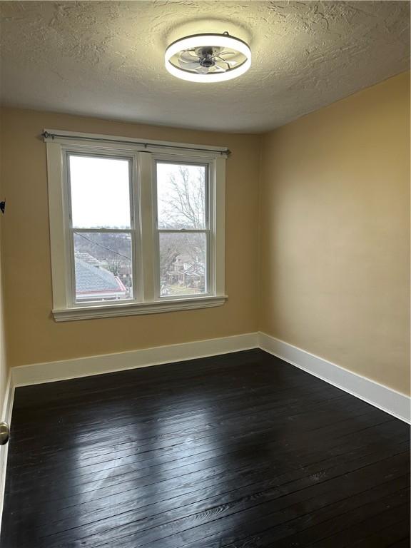 spare room with a textured ceiling and dark hardwood / wood-style flooring