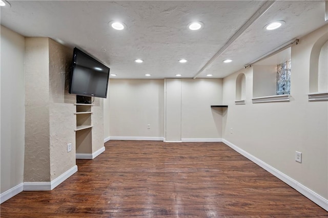 basement featuring a textured ceiling and dark wood-type flooring