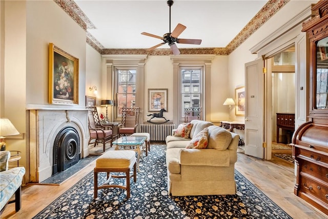 living area with ceiling fan, radiator heating unit, and a fireplace