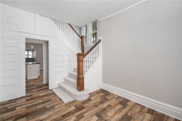 staircase featuring hardwood / wood-style floors and crown molding