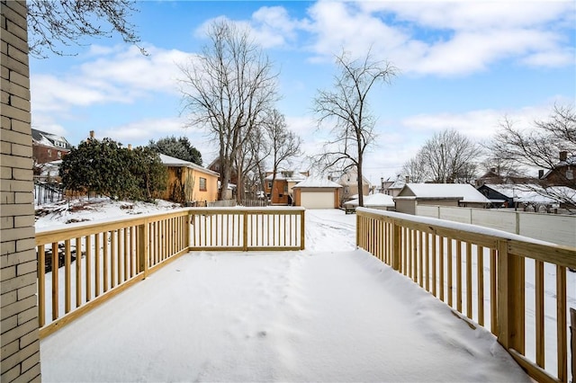 snow covered deck featuring an outbuilding and a garage