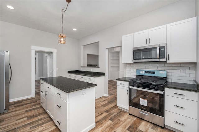 kitchen featuring appliances with stainless steel finishes, dark hardwood / wood-style floors, white cabinetry, and a kitchen island