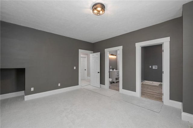 unfurnished bedroom featuring connected bathroom and light colored carpet