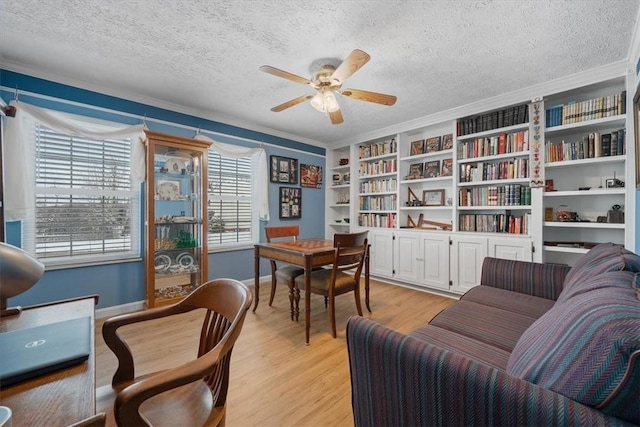 sitting room featuring crown molding, light hardwood / wood-style flooring, ceiling fan, built in shelves, and a textured ceiling