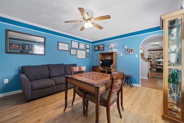 dining area featuring a textured ceiling, ceiling fan, crown molding, and light hardwood / wood-style flooring